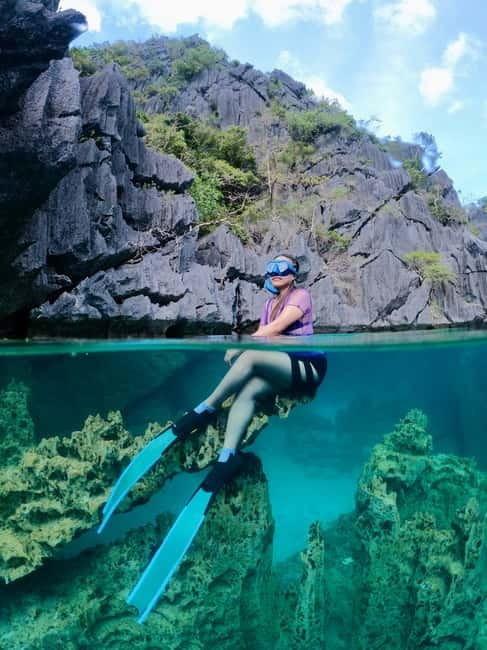 A snorkeller in the clear water below the limestone cliffs at Coron, Palawan